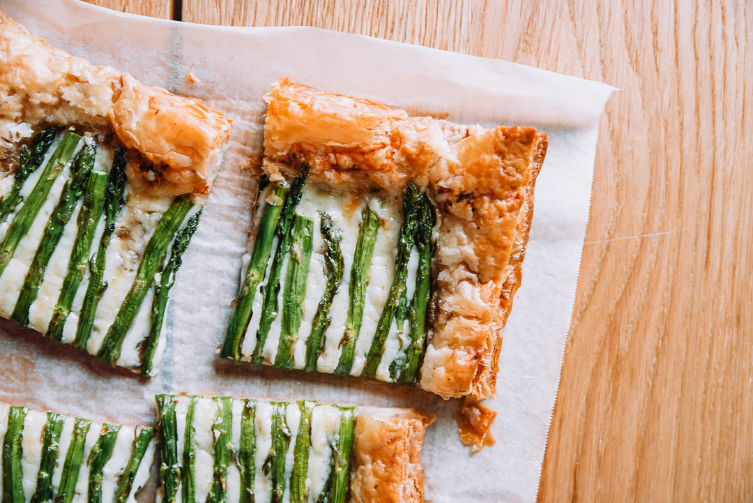 Spring asparagus tart on white parchment paper on wood table